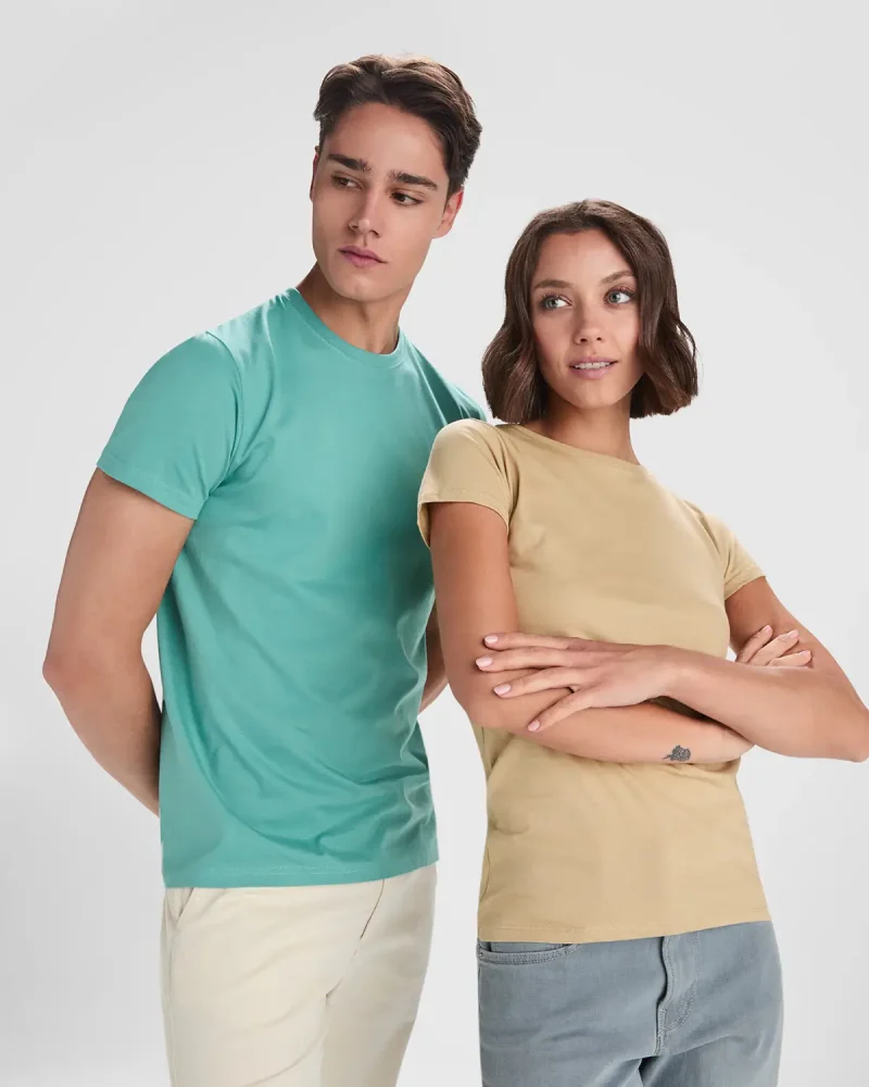 Two models pose side by side wearing pastel t-shirts: teal on the man and beige on the woman, looking off to the side.